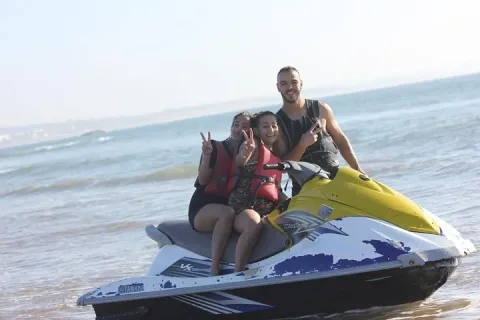 Jet ski skimming Agadir bay with a camel rider visible on the beach behind