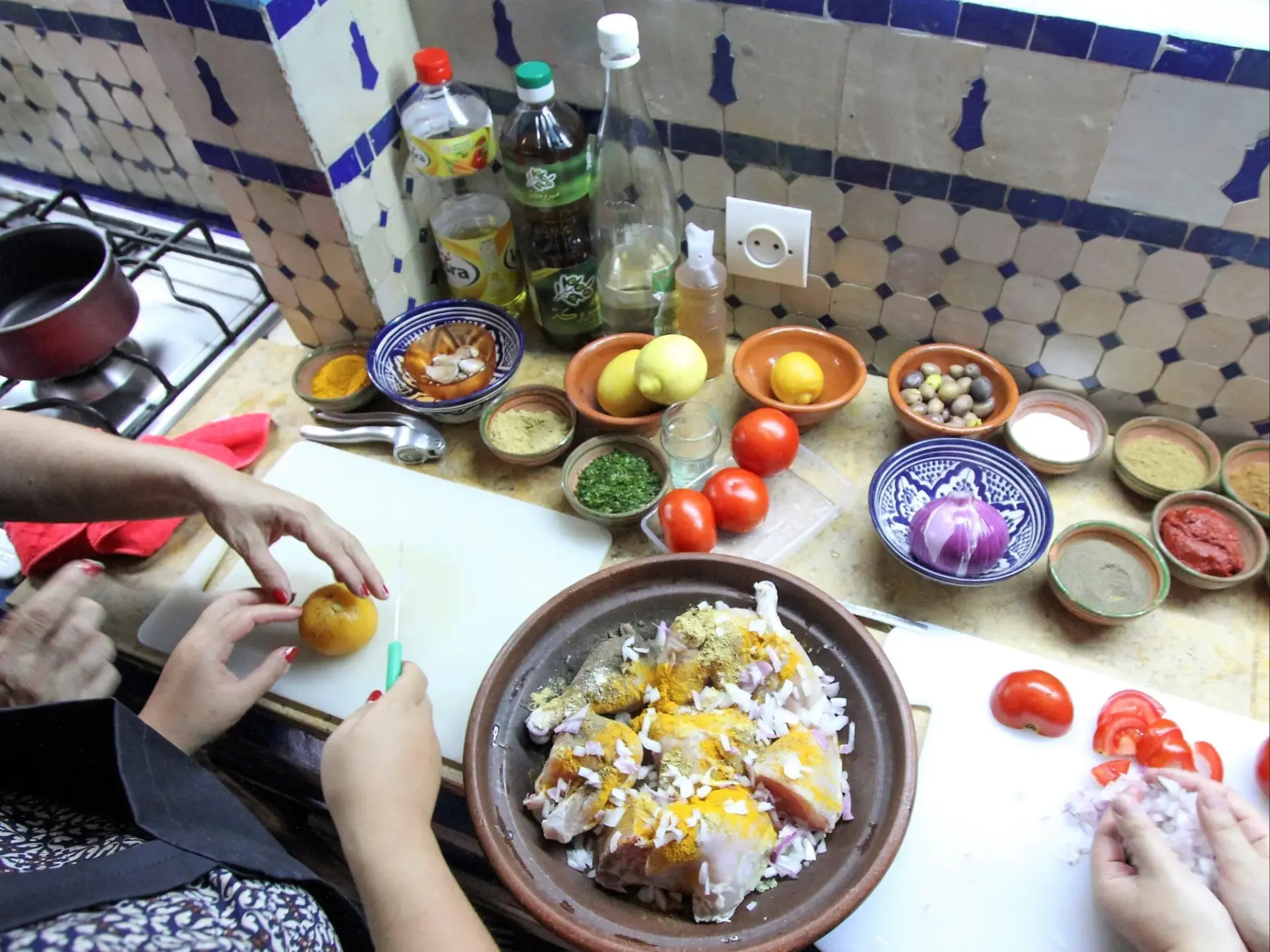 Hands gathered around a tagine and bowls of fresh vegetables during a cooking class in Agadir