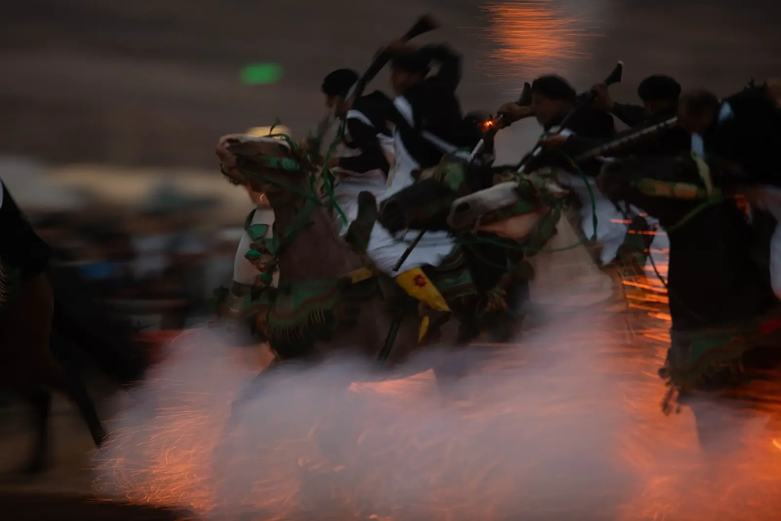 Moroccan riders in traditional dress performing a fantasia charge at dusk