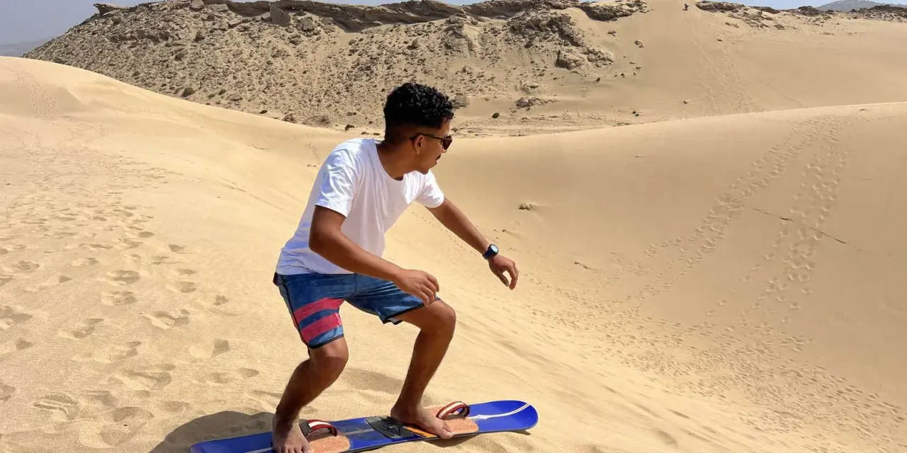 Traveller sandboarding down the Timlalin dunes near Agadir, Morocco